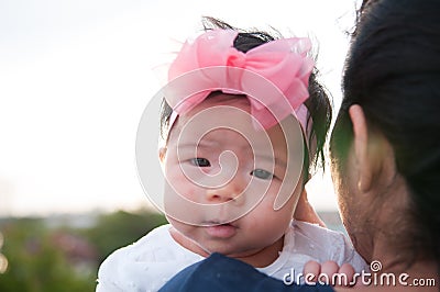 Mother day bonding concept with newborn baby nursing. Mother is holding newborn baby with flower pink headband with blue sky. Stock Photo