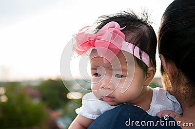 Mother day bonding concept with newborn baby nursing. Mother is holding newborn baby with flower pink headband with blue sky. Stock Photo