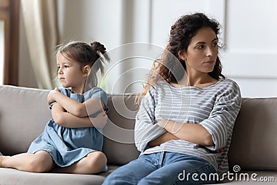 Mother disobedient daughter sit apart on sofa feeling discontent Stock Photo