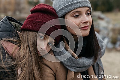 Mother and doughter teenager are walking on the street in warm autumn clothes Stock Photo