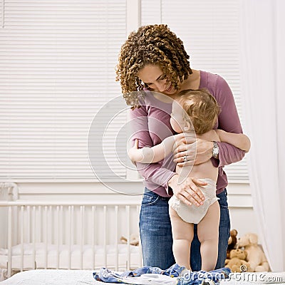 Mother dressing her son in bedroom Stock Photo