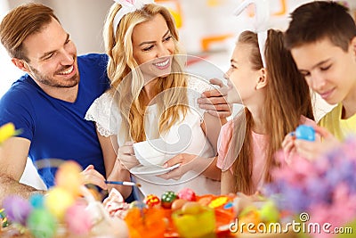 Mother drinks coffee while children coloring Easter eggs Stock Photo