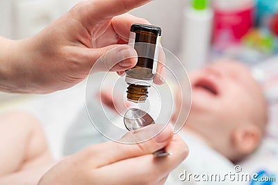 Mother drips drops from colic in the tummy of a small child. Close-up Stock Photo