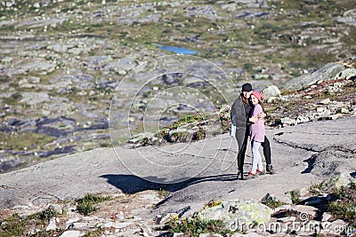 Mother embracing teen age daughter, standing on rock during hiking to trolltunga, copyspace. Norway Stock Photo