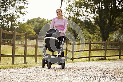 Mother Exercising By Running Whilst Pushing Baby Buggy Stock Photo