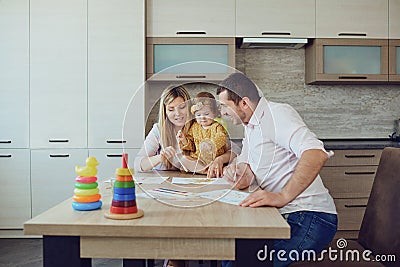 Mother, father and child draw together at the table. Stock Photo