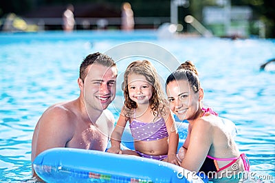 Mother, father and daughter in swimming pool. Sunny summer. Stock Photo