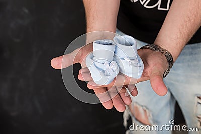 Father Hands Holding blue Newborn Baby Booties.Expectation for a baby. Mens hands with small shoes for unborn baby Stock Photo