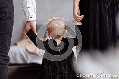 Mother, father hold hands daughter enjoy time together at home. View down the legs. Mother`s, father`s, baby`s day. concept of Stock Photo