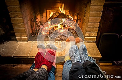 Mother father and kids sitting at cosy fireplace on Christmas time - Lovely family resting together on woolen socks at home fire Stock Photo