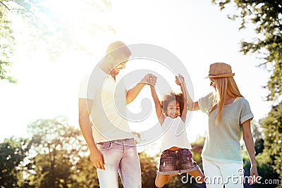 Mother and father swinging daughter Stock Photo