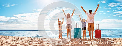 Mother and father with their children standing on the beach with suitcases. Stock Photo