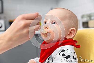 Mother is feeding baby boy with spoon. Healthy baby food at home Stock Photo