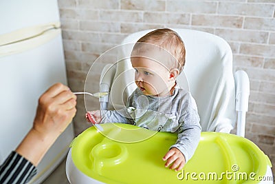 Mother feeding child. First solid food for young kid. Healthy nutrition for children Stock Photo