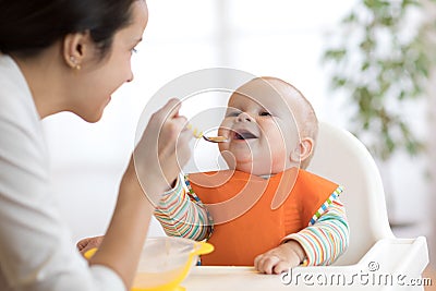 Mother feeding her baby with spoon. Mother giving healthy food to her adorable child at home Stock Photo