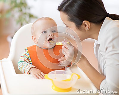 Mother feeding her baby with spoon. Mother giving healthy food to her adorable child at home Stock Photo