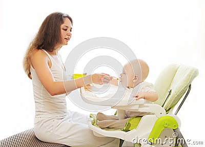 Mother feeds baby spoon sitting for table home Stock Photo