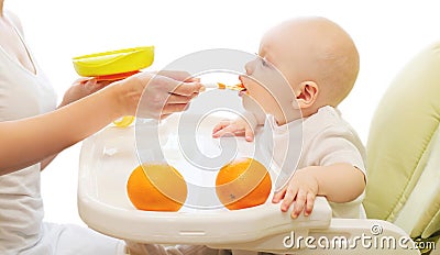 Mother feeds baby spoon on table home Stock Photo