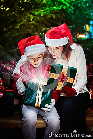 Mother gives her child a Christmas gift box with light rays and Stock Photo