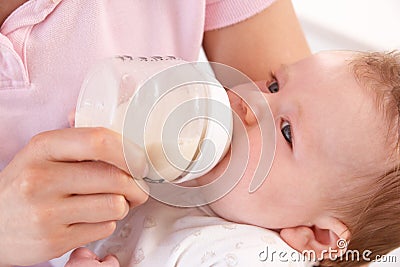Mother Giving Bottle To Baby Boy At Home Stock Photo