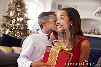 Mother Giving Christmas Presents To Son At Home Stock Photo