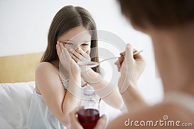 Mother Giving Cough Syrup To Reluctance Daughter Stock Photo