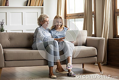 Mother and grownup daughter sitting on couch using computer Stock Photo
