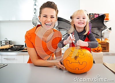 Mother with halloween dressed daughter creating Jack-O-Lantern Stock Photo