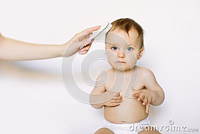 Mother hand is combing baby hair after bathing. Hygiene and care concept Stock Photo