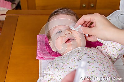 Mother hands cleaning eyes of baby with cotton Stock Photo