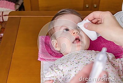 Mother hands cleaning eyes of baby with cotton Stock Photo