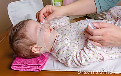 Mother hands cleaning eyes of baby with cotton Stock Photo