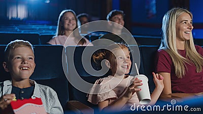 Mother with happy small children in the cinema, watching film. Stock Photo