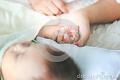 The mother held the hand of the little son lying on the bed Stock Photo