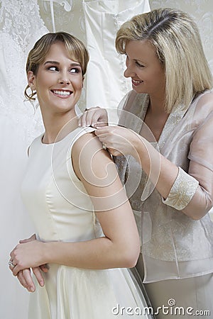Mother Helping Bride With Wedding Dress Stock Photo