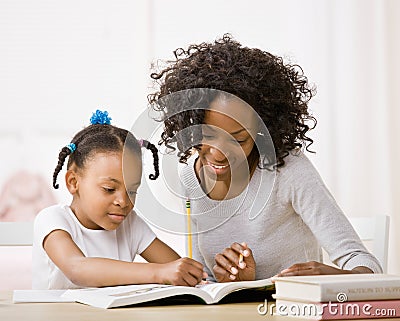 Mother helping daughter do homework in workbook Stock Photo