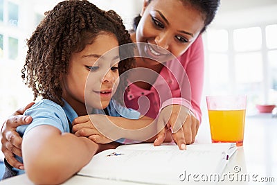 Mother Helping Daughter With Homework In Kitchen Stock Photo