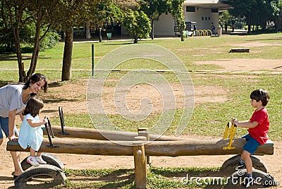 Mother Helping Her Kinds use a Teeter Totter Stock Photo