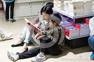 Mother helping son reading in the bookstore Editorial Stock Photo