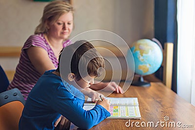 Mother helps son solving mathematics homework at desk Stock Photo