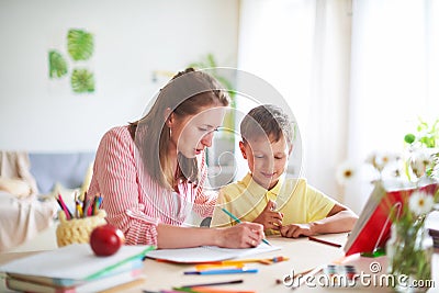 Mother helps son to do lessons. home schooling, home lessons. the tutor is engaged with the child, teaches to write and count Stock Photo