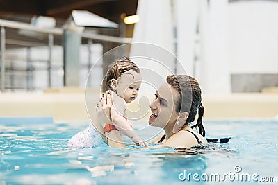 Mother with her baby daughter swim in the pool in waterpark Stock Photo