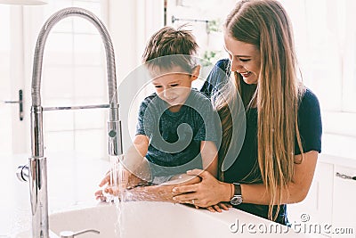 Mother with her child playing in kitchen sink Stock Photo