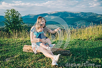 Mother with her daughter on her knees point somewhere Stock Photo