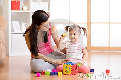 Mother and her kid playing with colorful logical sorter toy Stock Photo