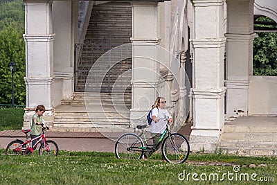 Mother and her son going with bicycles in the park, side view. Family spending active vocations in the summer. Editorial Stock Photo