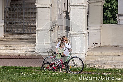 Mother and her son going with bicycles in the park, side view. Family spending active vocations in the summer. Editorial Stock Photo