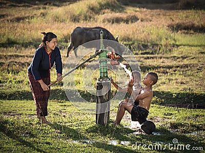 Mother her sons shower outdoor from Groundwater pump. Stock Photo