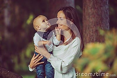 A mother holding a cute smiling baby in the woods Stock Photo