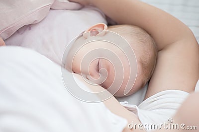 Mother holding newborn baby in an embrace and breastfeeding. Mother is breastfeeding her baby. Newborn breastfeed. Happy Stock Photo